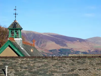 a church with a steeple on top of a brick wall at Croft Cottage in Braithwaite