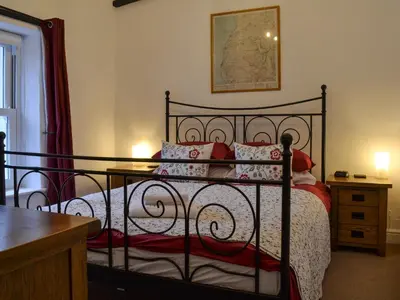 a bedroom with a black bed with red pillows at Croft Cottage in Braithwaite