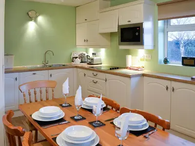 a kitchen with a wooden table with plates and glasses on it at Beech End in Braithwaite
