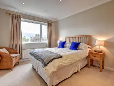 a bedroom with a bed with blue pillows and a window at Roseworth in Portinscale