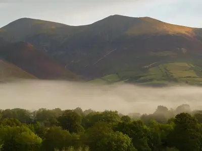 a foggy valley with trees and mountains in the background at Bracken Howe in Portinscale