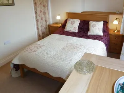 a bedroom with a bed and two tables at Bracken Howe in Portinscale