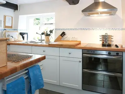 a kitchen with white cabinets and a stove top oven at Blease Cottage in Threlkeld