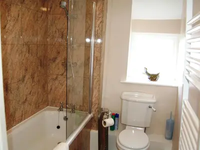 a bathroom with a shower and a toilet and a tub at Blease Cottage in Threlkeld