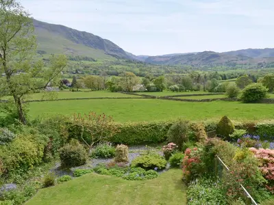 a garden with flowers and a river in a field at Cropple Howe in Threlkeld