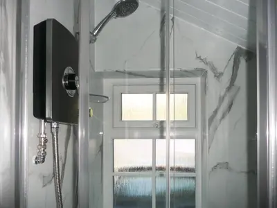 a shower with a glass door and a window at Cropple Howe in Threlkeld