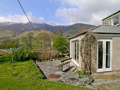 a bench sitting outside of a house with mountains in the background at Netherend in Threlkeld