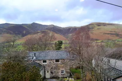 an old stone house with mountains in the background at Netherend in Threlkeld