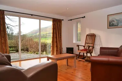 a living room with a couch and a chair and a large window at Netherend in Threlkeld