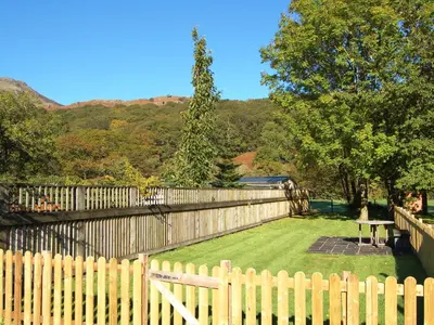 a wooden fence in front of a yard with a table at Brasscam in Rosthwaite