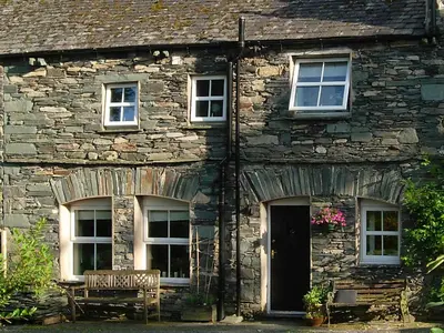 a stone house with a bench in front of it at Chapelfield Cottage in Rosthwaite
