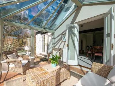 a conservatory with a glass roof with chairs and a table at Lookin How in Dockray