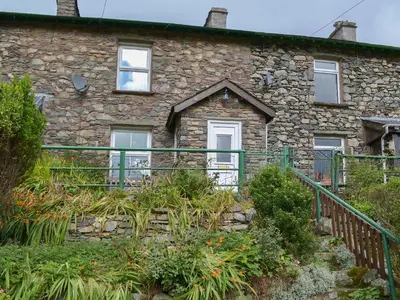 a stone house with a green fence in front of it at 3 Highrake in Glenridding