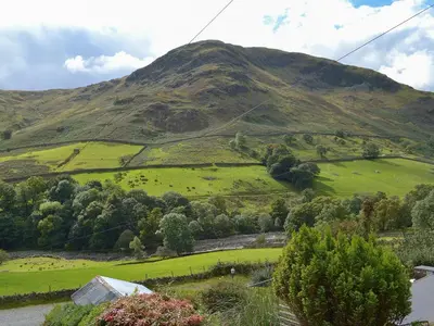a green hillside with a mountain in the background at 3 Highrake in Glenridding