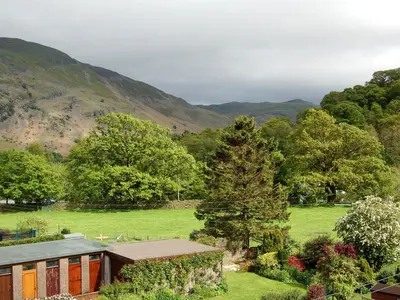 a house in a field with mountains in the background at Molly's Cottage in Glenridding