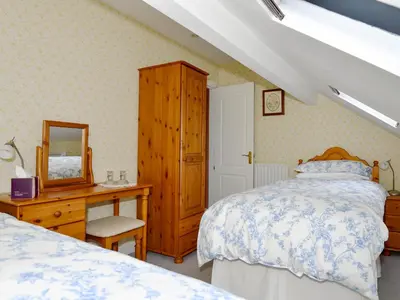 a bedroom with a bed and a dresser and a mirror at Molly's Cottage in Glenridding
