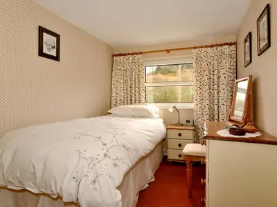 a bedroom with a bed and a window at Molly's Cottage in Glenridding