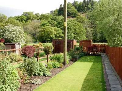 a garden with a fence and green grass at Molly's Cottage in Glenridding