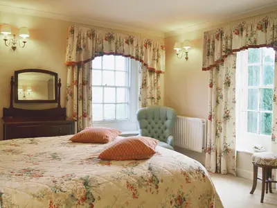 a bedroom with a bed and a mirror and a chair at Laundry Cottage in Uldale