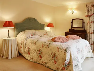 a bedroom with a bed and a mirror and lamps at Laundry Cottage in Uldale