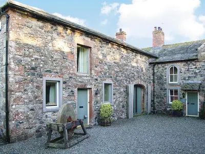 a stone building with a bench in front of it at The Old Stables in Uldale