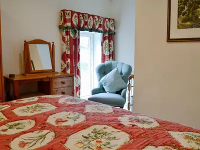 a bedroom with a bed and a chair and a mirror at The Old Stables in Uldale