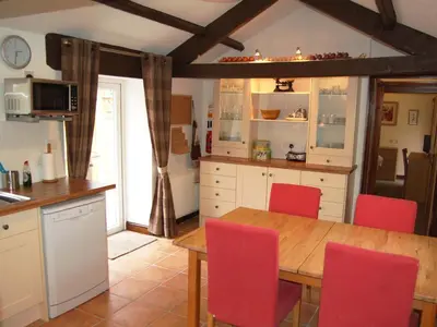 a kitchen with a wooden table and red chairs at Nuthatch Cottage in Westward