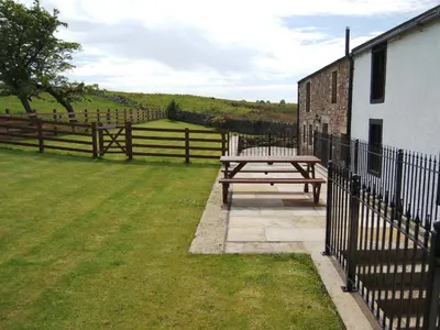 a wooden picnic table next to a fence at Greenrigg Cottage in Caldbeck