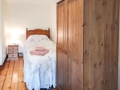 a bedroom with a bed and a large wooden cabinet at Greenrigg Cottage in Caldbeck