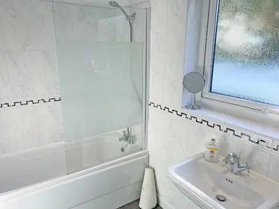 a bathroom with a tub and a sink and a window at Fourwinds in Keswick
