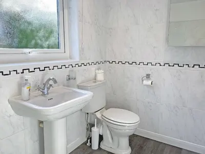 a white bathroom with a toilet and a sink at Fourwinds in Keswick