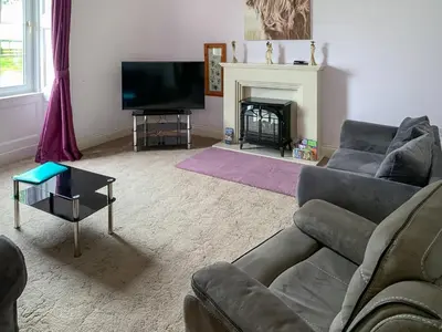 a living room with a couch and a tv and a fireplace at Bonshawside Farmhouse in Kirtlebridge