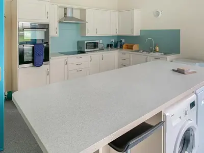 a kitchen with white cabinets and a washer and dryer at Bonshawside Farmhouse in Kirtlebridge