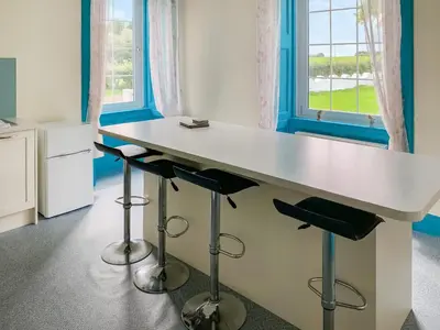 a kitchen with a large white table and stools at Bonshawside Farmhouse in Kirtlebridge