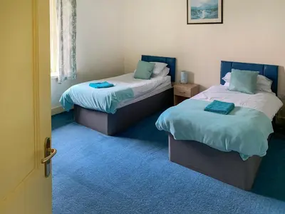 two beds in a room with blue carpet at Bonshawside Farmhouse in Kirtlebridge
