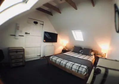 a bedroom with a bed and a tv in a attic at Ayrshire Holiday Cottage in Girvan