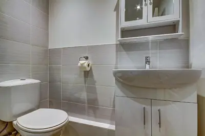 a white bathroom with a toilet and a sink at Garden Gate Upper Apartment in Prestwick
