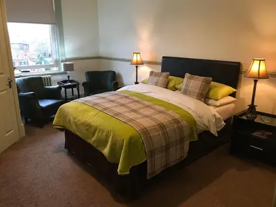 a bedroom with a bed and two chairs and a window at Abberley House in Carlisle