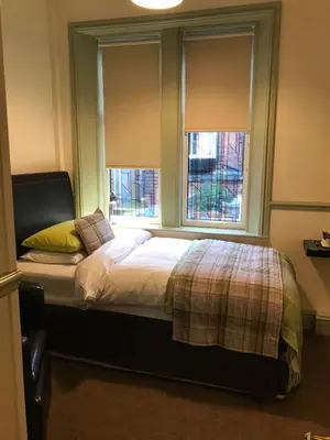 a bedroom with a bed with two windows at Abberley House in Carlisle