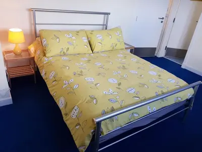 a bed with a yellow comforter and pillows at Barholm Accommodation in Creetown