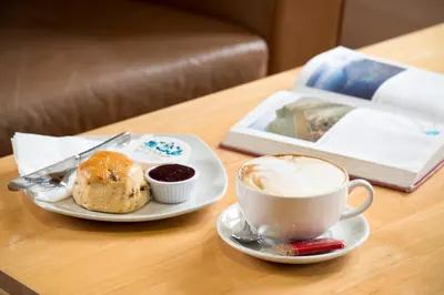 a cup of coffee and a plate of food on a table at The Lodge In The Vale in Thirlmere