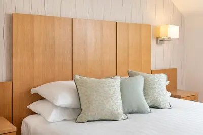 a bed with white pillows and a wooden headboard at The Lodge In The Vale in Thirlmere