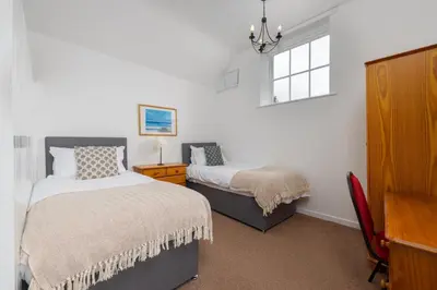 a bedroom with two beds and a window at Muncaster Castle Coachman's Quarters in Ravenglass
