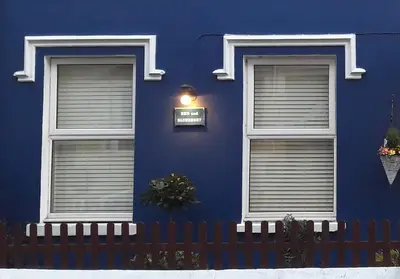a blue building with two windows and a fence at Blueberry Two Bedroom Suite for 1, 2 or 3 people in Douglas