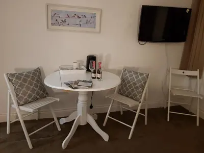 a white table with two chairs and a tv at Blueberry Two Bedroom Suite for 1, 2 or 3 people in Douglas