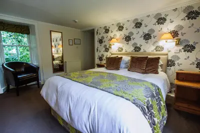a bedroom with a large bed and a chair at Selkirk Arms Hotel in Kirkcudbright