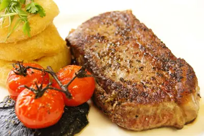 a steak with tomatoes and bread on a plate at Selkirk Arms Hotel in Kirkcudbright