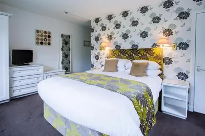 a bedroom with a large bed and a tv at Selkirk Arms Hotel in Kirkcudbright