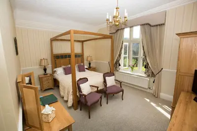 a bedroom with a canopy bed and purple chairs at Hazel Bank Country House Borrowdale Valley in Rosthwaite