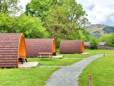 a group of huts in a field with a table at YHA Borrowdale in Rosthwaite
